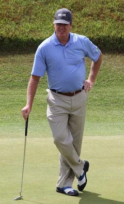 steve elkington stands with a putter on a green, with one hand on his hip