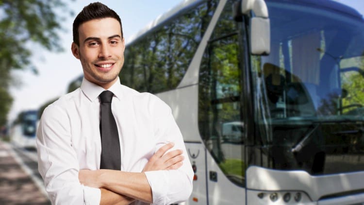 a charter bus driver stands in front of a bus before a trip