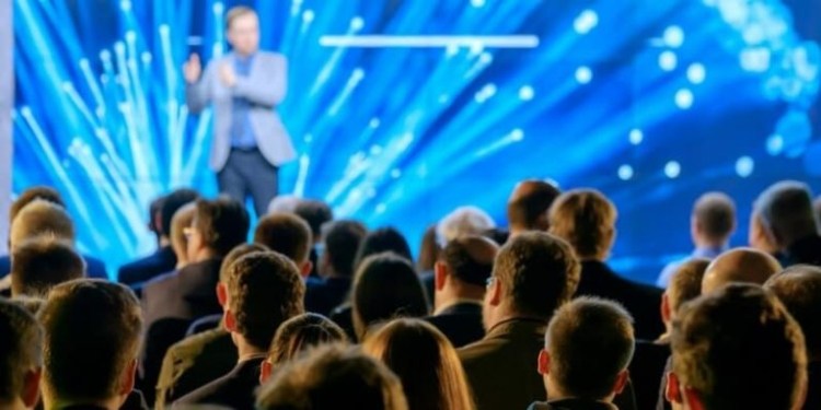 A man giving a lecture in a blue auditorium