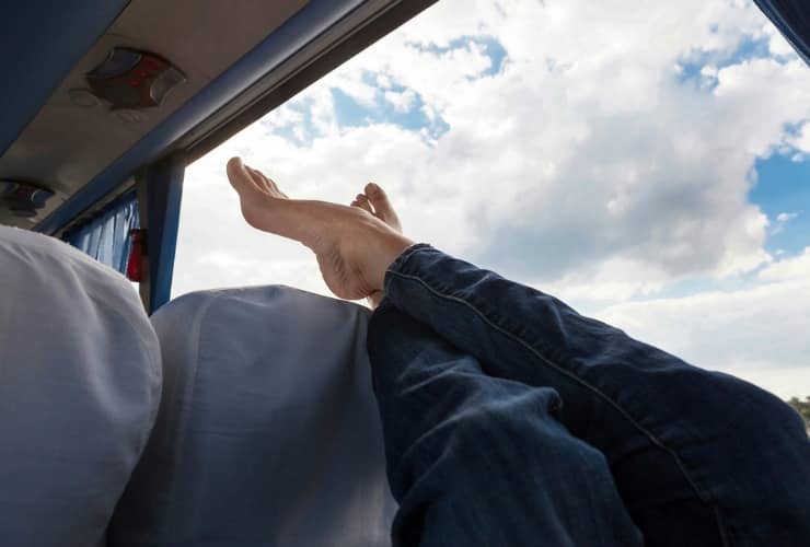 person kicking their feet up and enjoying extra leg room on a charter bus