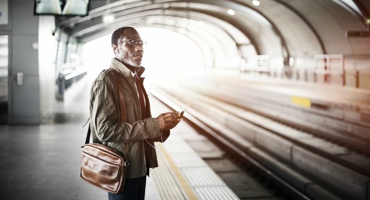 a man, holding a laptop bag, waits for a train in a tunnel