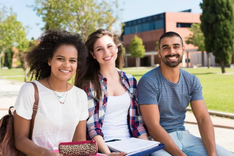 Three college students smiling at the camera