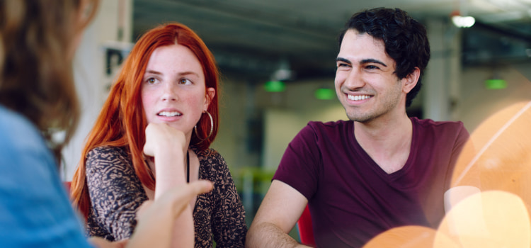 a group of high school students talk and laugh in a cafeteria