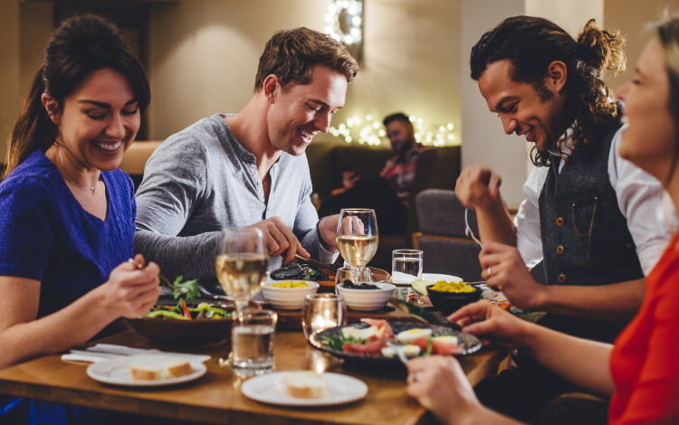 A group of friends in nice clothes enjoy dinner at a restaurant