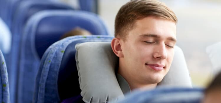 man sleeping on a charter bus with a neck pillow