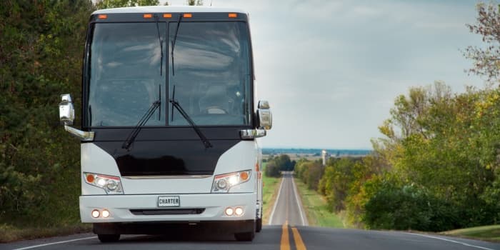 charter bus driving on a long country road