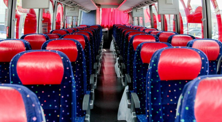 the interior of a charter bus with blue and red seats
