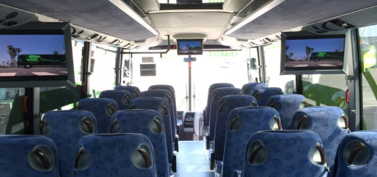 Interior of a charter Bus with TV screens and blue seats