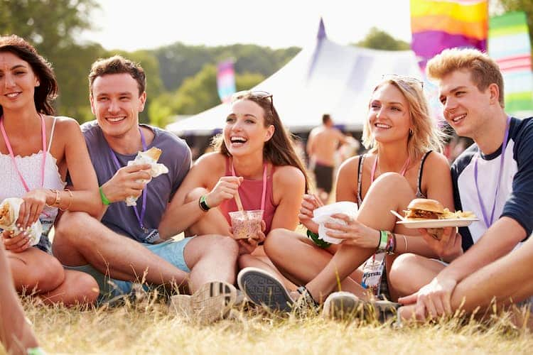 People sitting on ground eating at food festival