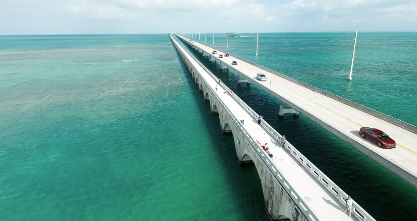 cars drive across the highway bridge that connects the Florida Keys, open ocean underneath