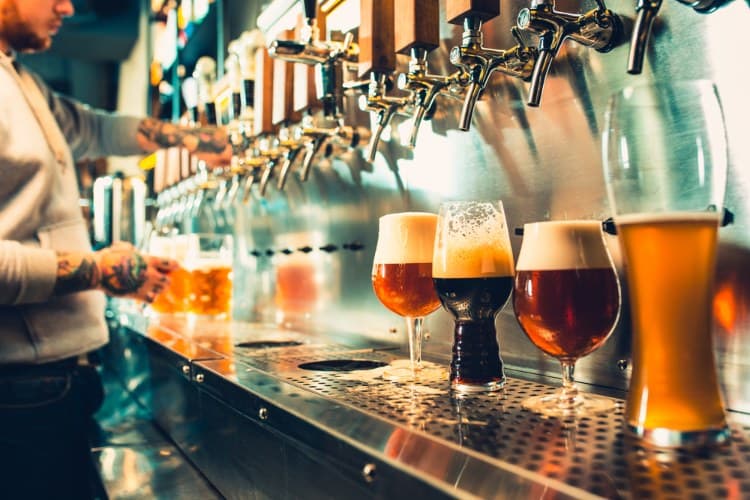 glasses of craft beer lined up under a tap