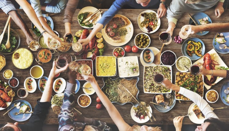 overhead view of a dining table full of small plates as friends share a large meal