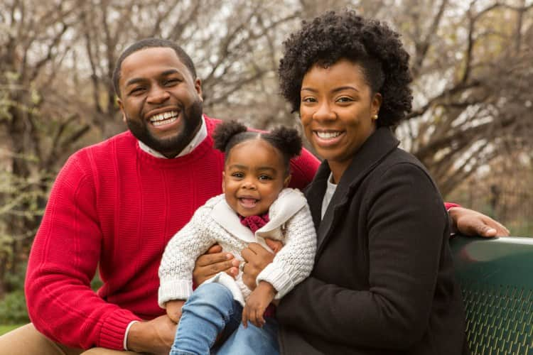 A family holding a child and smiling