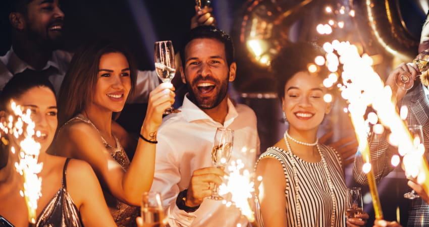 a group of friends ignite sparklers and sip champagne on New Years Eve