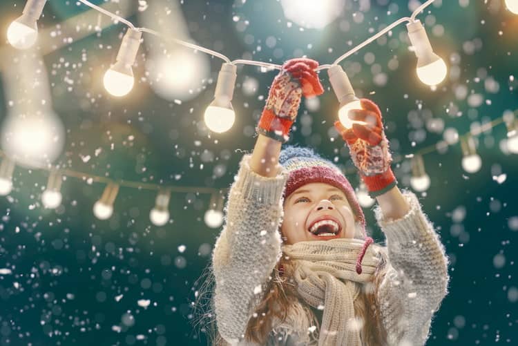 a girl reaches for a Christmas light during Austin's Winter Wonderland at the Circuit