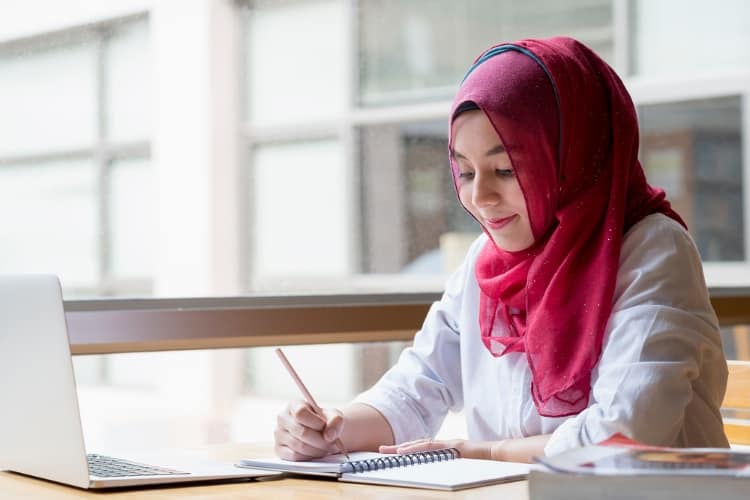 A college student is writing in a notebook