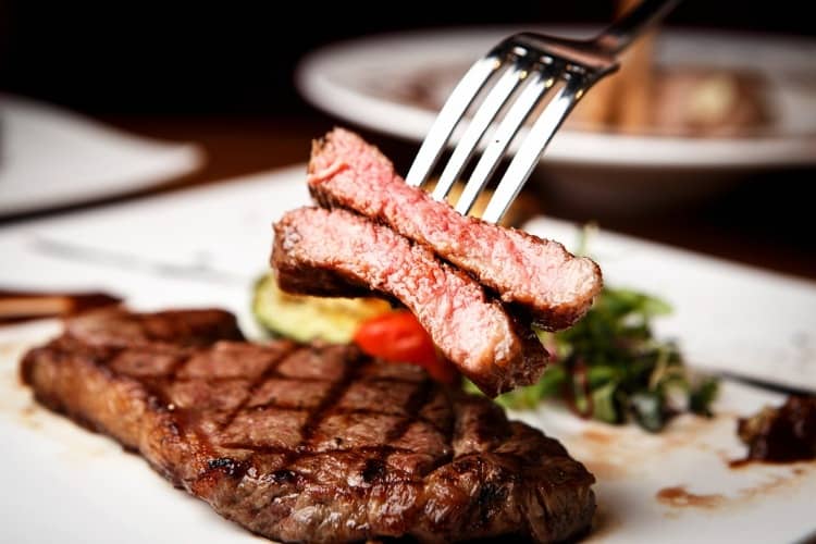 A cut steak on a plate with vegetables