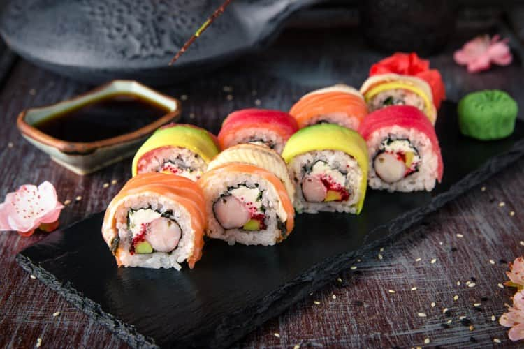 Sushi hand rolls on a black plate at a restaurant 