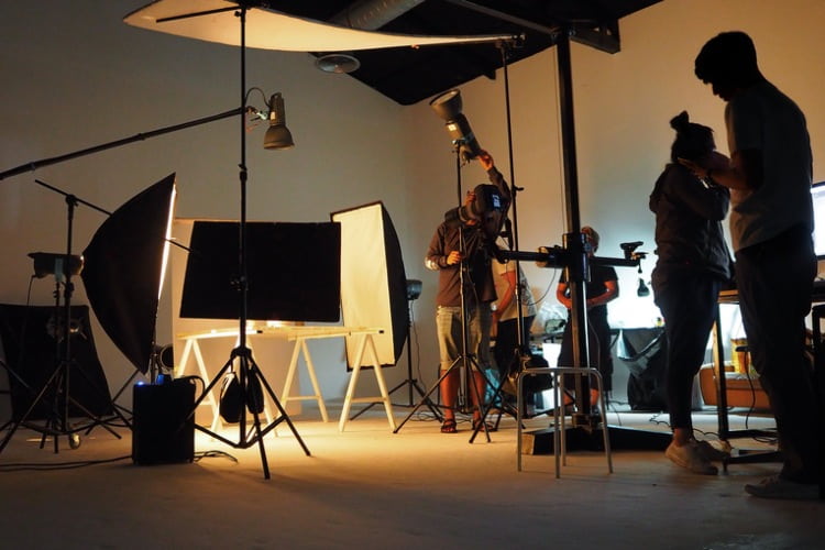 a film crew sets up lighting around a shoot