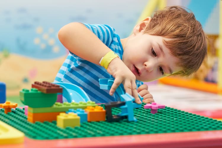 child playing and building with colorful plastic bricks table