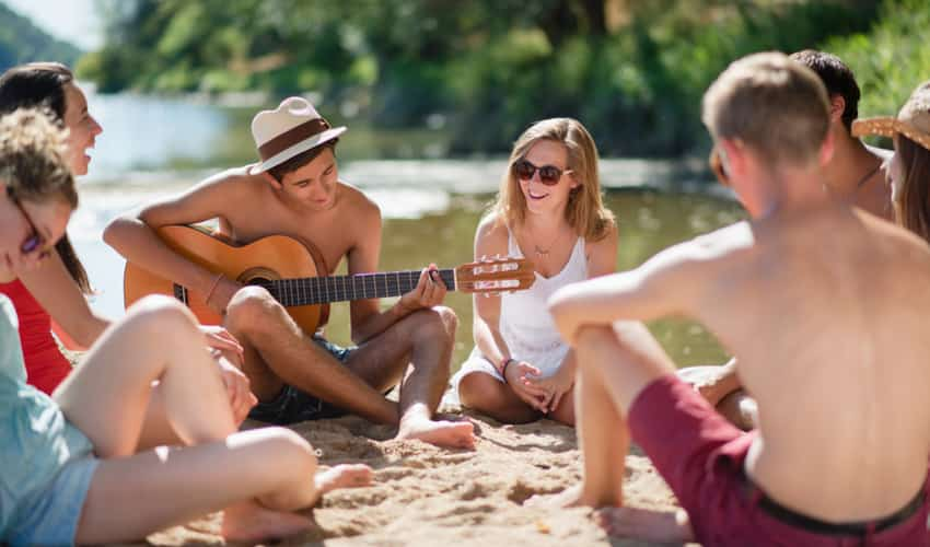 a group of young people playing music on the beach