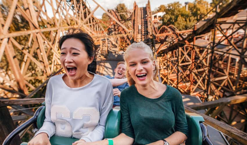 Two women laughing and riding a wooden rollercoaster