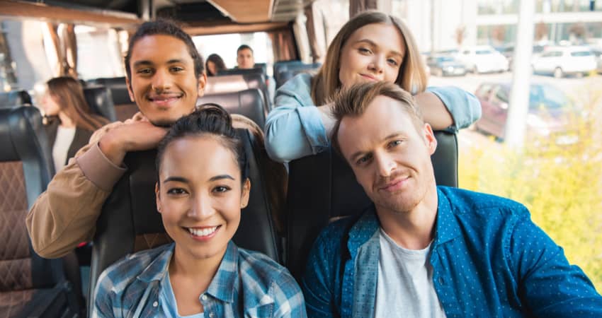 A group of young tourists smiling on a charter bus