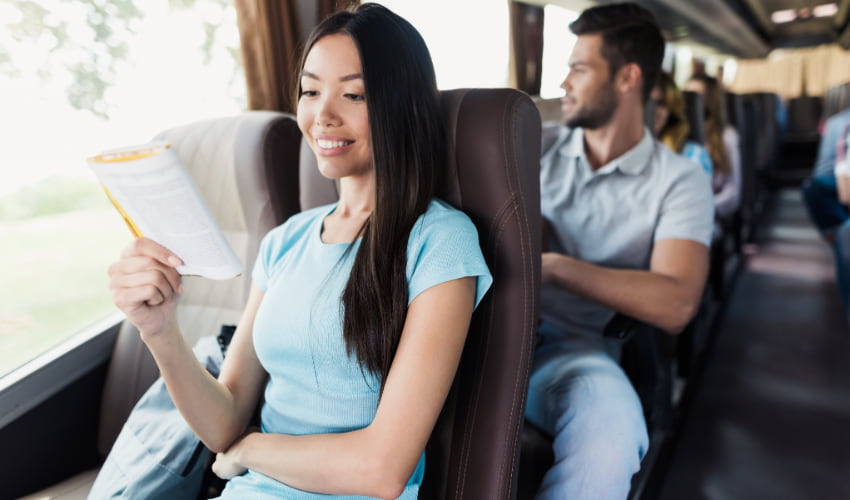 a woman reads a book on a charter bus