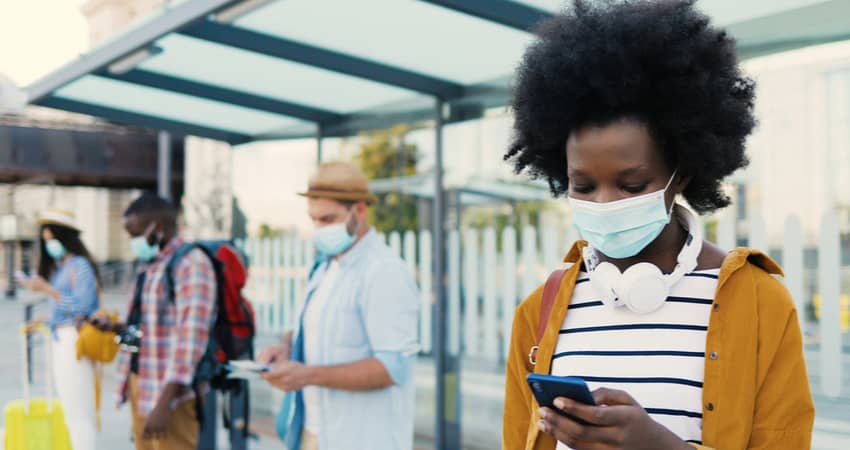 A group of people waiting for their charter bus while wearing masks