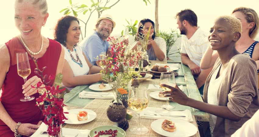 A group of friends gather around the table, talk, and drink white wine