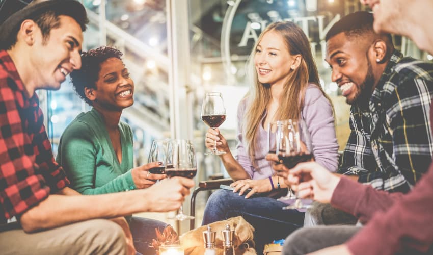 A group of people laugh and drink wine in a wine tasting venue