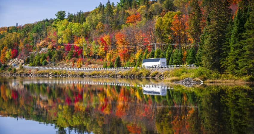 a bus drives past beautiful fall scenery on a byway