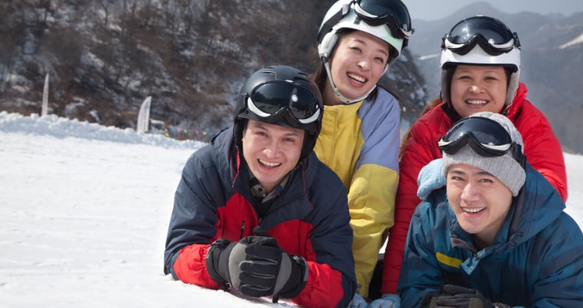 two couples pose for a picture in the snow on a ski slope