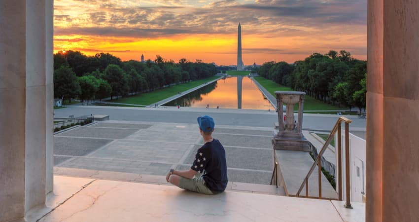 A person sitting at the Lincoln Memorial at sunset