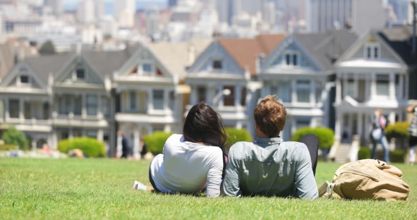 A couple lay on the grass in Alamo Square park, near the Painted Ladies