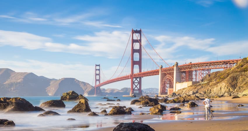 A couple with a tripod photographs the Golden Gate Bridge from Baker Beach