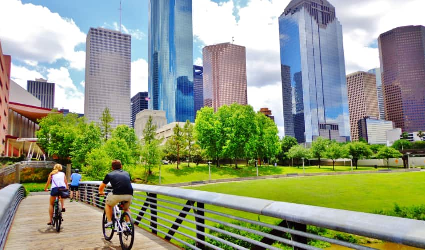 Two people ride bikes on the Buffalo Bayou Hike and Bike Trail in Houston