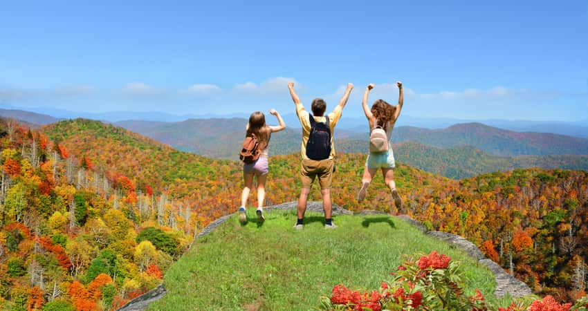 People jumping in the air at the top of a mountain along the Blue Ridge Parkway in Asheville