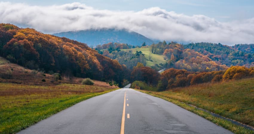 A close up of the Blue Ridge Parkway with mountains covered by fog in the distance