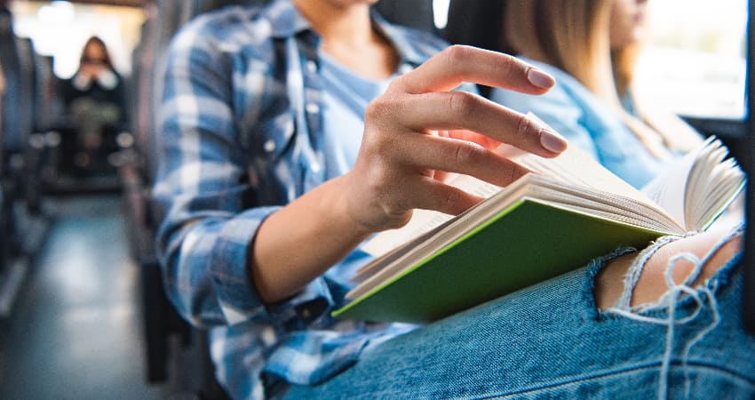 A woman reads a book while riding on a charter bus