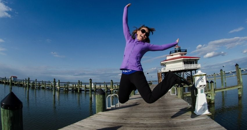 Woman jumping for joy on a lighthouse dock in the Chesapeake Bay