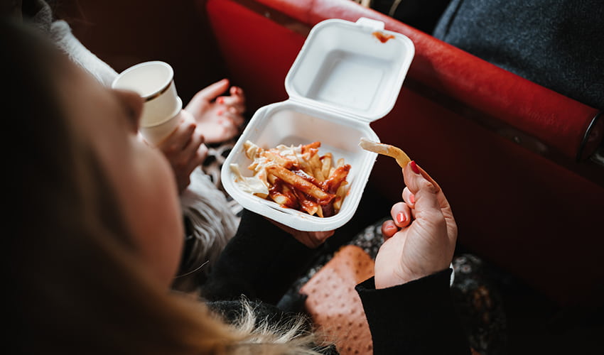 A woman eats french fries on a bus