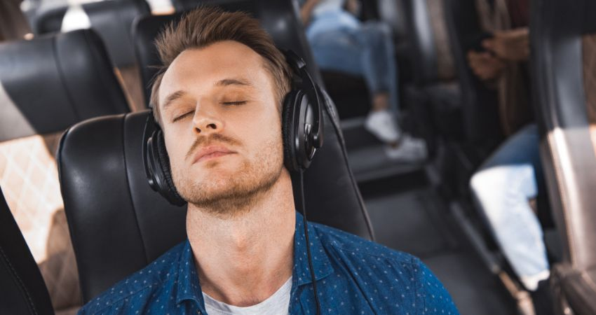 Man sleeping on a bus listening to music with headphones