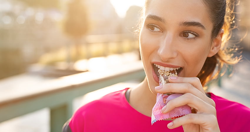 A woman eats a granola bar