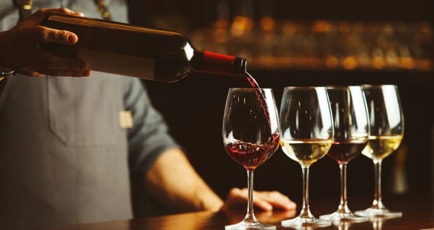 A bartender pouring a flight of wine