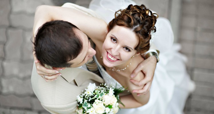 A happy couple look up to the camera on their wedding day