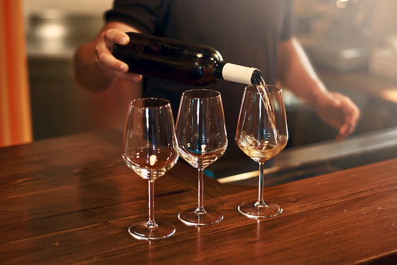 Person pouring wine into glasses