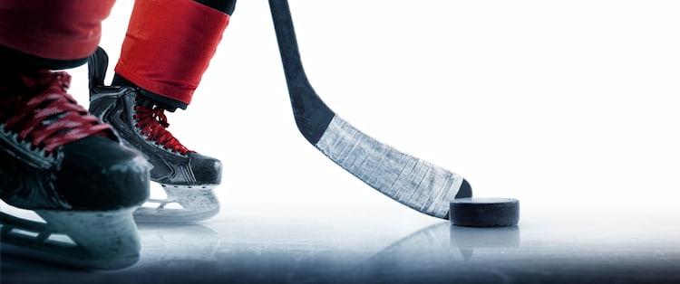 a hockey puck on an ice rink and a hockey stick being held up to it