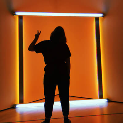a person's silhouette in front off a neon art piece in the moma