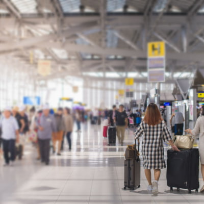 travelers walk through a busy airport with their bags